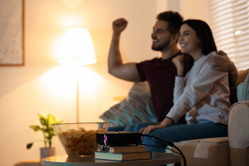 Young couple watching TV at home, focus on video projector