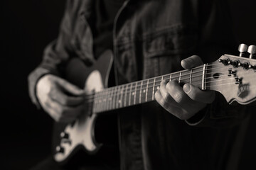 Man playing guitar in darkness, closeup. Black and white effect