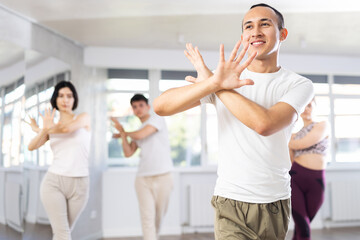 Fototapeta premium Portrait of active young man enjoying modern energetic dancing in group at street dance studio