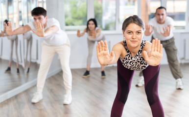 Obraz premium Group of young men and women doing warm up before dance class in studio
