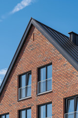 Closeup of red brick residential house with windows and blue sky. Real estate concept.