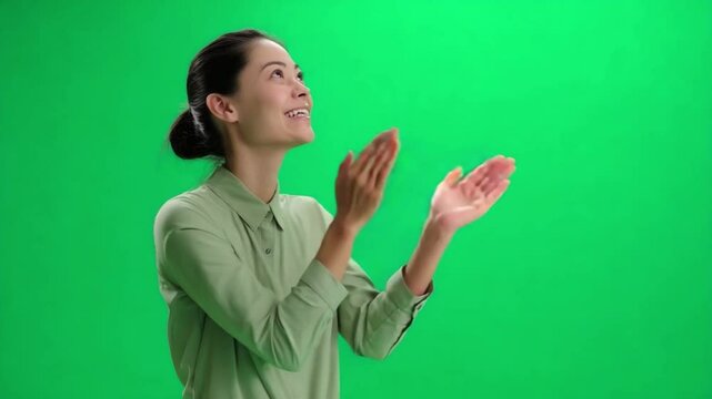 Woman Applauding on Green Screen: A joyful woman with dark hair and a gentle smile claps her hands in appreciation, set against a vibrant green screen, ideal for chroma keying and compositing. 