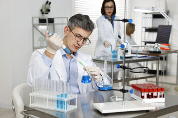 Scientist with micropipette and flask working in laboratory