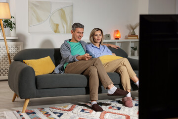 Obraz premium Lovely couple watching TV on sofa at home