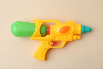 Bright plastic water gun on beige background, top view