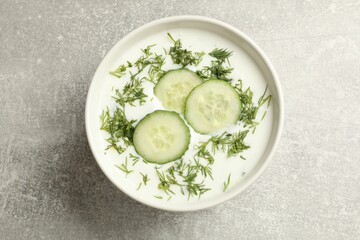 Tasty cucumber soup with dill in bowl on grey textured table, top view