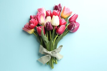 Obraz premium Bouquet of beautiful tulips on light blue background, top view