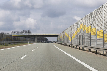 Modern highway with sound barriers. Yellow and grey wall. Overpass bridge ahead. Road...