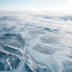 Fototapeta premium Aerial view of a frozen, snow-covered landscape with winding waterways.
