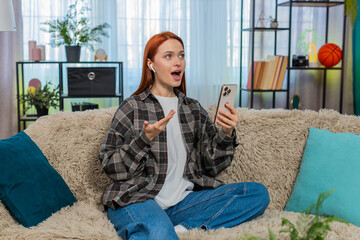 Young woman at home learning new language using mobile app and repeating words aloud with focus and...