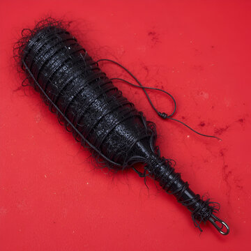 Black leather flogger on a vibrant red background.