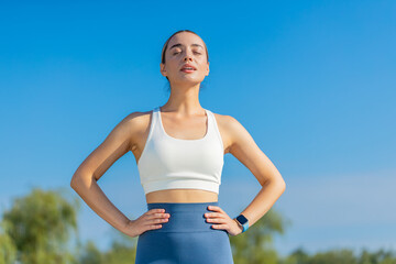 Young Caucasia female runner is short of breath after a fast sprint run in urban city park. Fit...