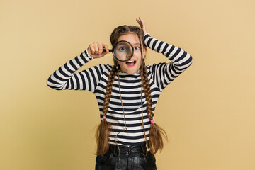 Investigator researcher scientist preteen child girl kid holding magnifying glass near face,...