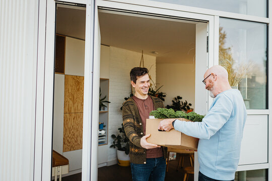 Caregiver Delivering Food At Door Of young Man
