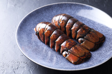 Raw lobster tails on black table, closeup