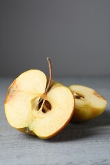 Halves of overripe apple on grey wooden table, closeup