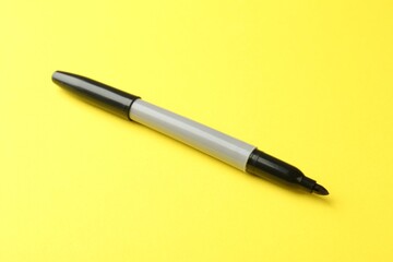 One black marker on yellow background, closeup