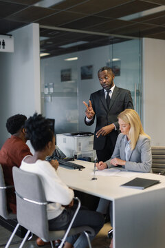 Agent talking to car buyers while his colleague finalizing contract
