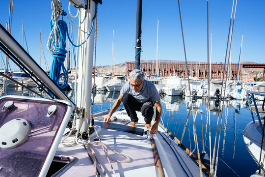 Focused mature man cleaning solar panel on boat