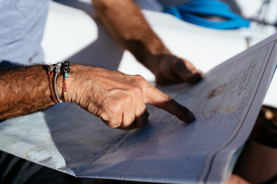 Hand of faceless person studying map on daytime