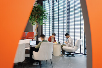 Multiethnic team of IT company working and using gadgets in office