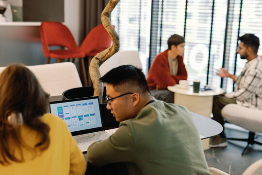 IT employees developing design of app on laptop near colleagues
