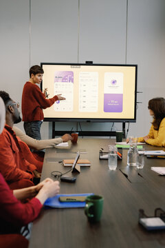 Woman showing presentation of new interface for app to team