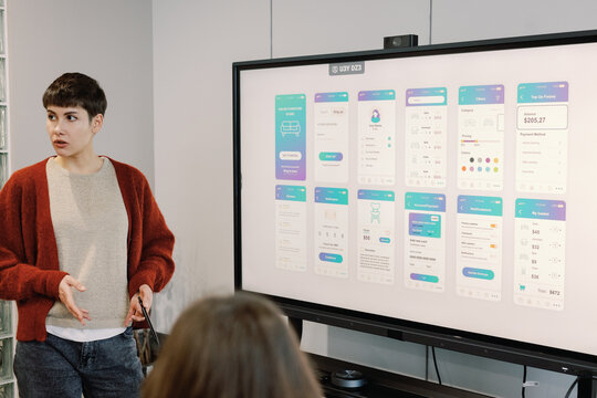 Woman showing presentation of new design for digital app to IT team - Powered by Adobe
