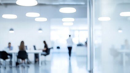 Blurred office interior with white walls and people working in the background, creating an abstract work environment concept. 