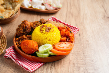 Nasi Kuning. Yellow rice is a typical Indonesian food. This food is made from rice cooked with turmeric, coconut milk, spices and served with fried chicken, egg balado, sambal, and crackers. 