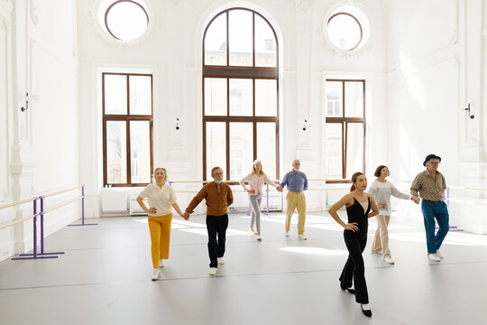 Teacher demonstrating dance moves to elderly students at dance school