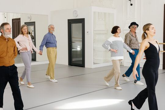 Focused retirees repeating dance steps after teacher at dance studio