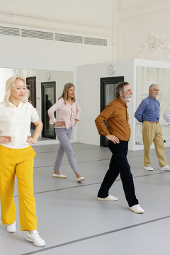 Group of retirees learning basic dance steps at dance school