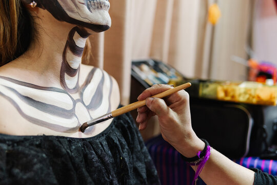 A person being painted with skeleton-like designs