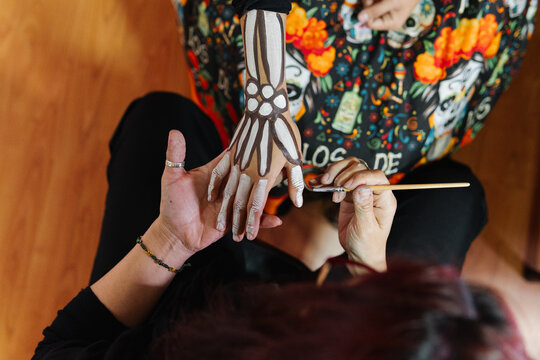 Unrecognizable makeup artist painting a pair of skeleton hands