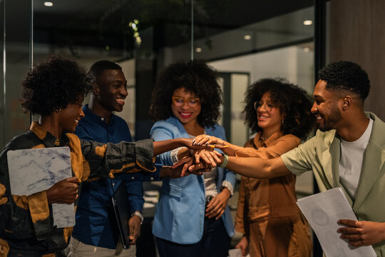 Happy enthusiastic people stacking hands in office