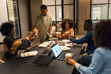 Young employee giving fresh takeaway coffee to colleagues at office