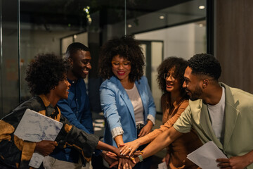 Smiling colleagues stacking hands in modern office