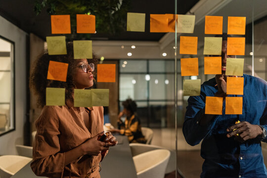 Happy man putting sticky notes on glass wall