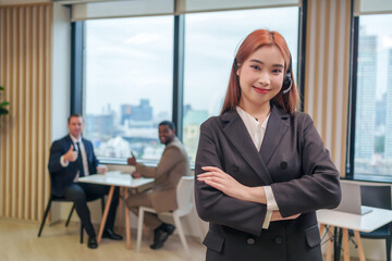 portrait young attractive woman office worker in suit wears headsets standing crossed arms at office,posing to camera