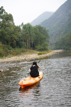 Asian woman rowing in a stream in the forest outdoors