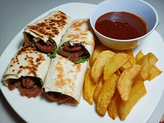 Kebab on White Plate. A delicious Kebab wrap with spicy meat, lettuce, tomato, and sauce.