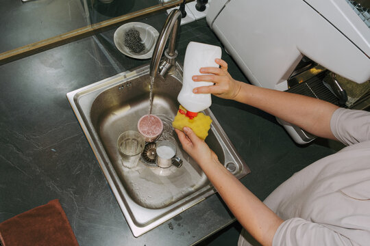 Owner washing dishes in small cafe during busy morning hours