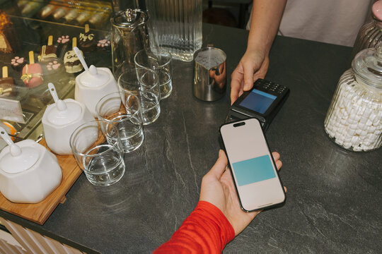 A customer who makes payments in a cafe using a smartphone