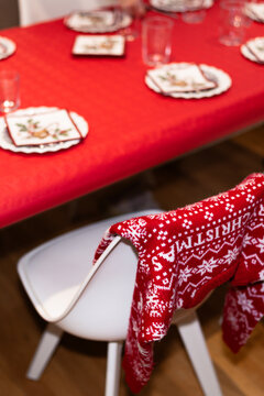 Christmas sweater hanging on a chair near a table set