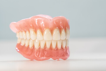 Close-up of a dental prosthetic model with artificial teeth and gums on a wooden surface. Ideal for dental care imagery