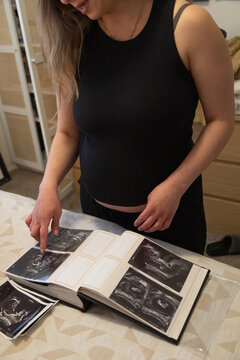 Pregnant woman looking at sonogram photos in her bedroom 