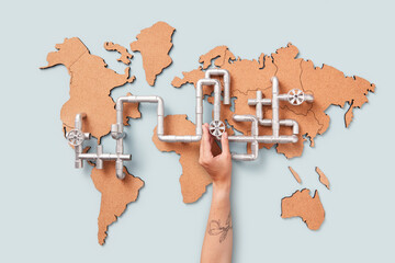 Man hand opening gas tap on pipe above world map with fuel transit