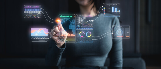 A woman interacts with futuristic digital data visualizations and analytics dashboards using virtual touchscreen technology.