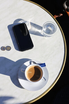 Espresso and Smartphone on Round Marble Table with bronze rim